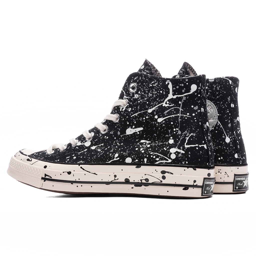 6.5W black Converse with red paint splattered on them.